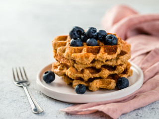 Easy healthy gluten free oat waffles with copy space. Stack of appetizing homemade waffles with oat flour decorated blueberries, on plate over light gray cement background