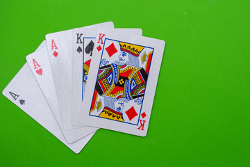 Full house hand of cards on bright green flat lay in a game of texas holdem poker gambling at a casino concept.