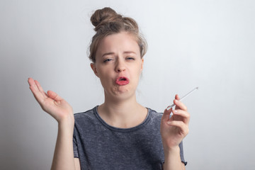 Young caucasian woman girl doesn't like smoking a cigarette, funny disgusted face 