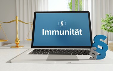 Immunität – Recht, Gesetz, Internet. Laptop im Büro mit Begriff auf dem Monitor. Paragraf und Waage.