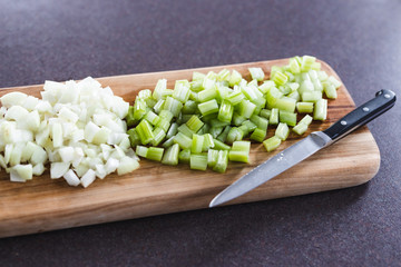 plant-based food, chopped onions and celeri on cutting board with knife