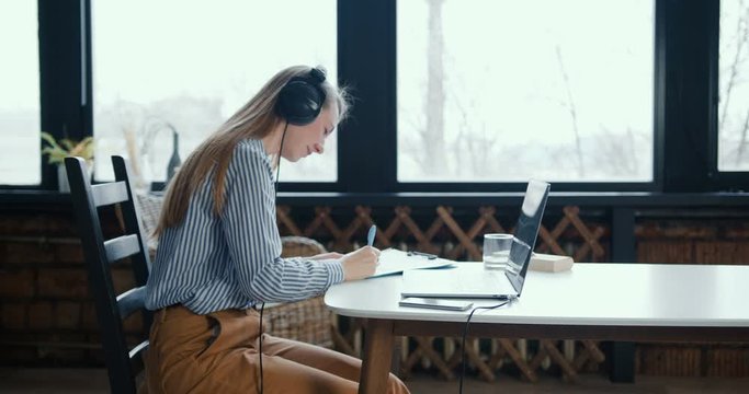 Working from home. Side view happy young Caucasian tutor woman using laptop video conference for e-learning studies.