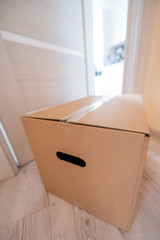 The concept of contactless delivery during the quarantine period. Cardboard box with online purchase at the open entrance door in case of danger of the spread of coronavirus.