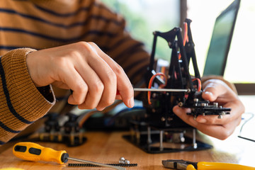 Young man code a metal car robot and an electronic board.