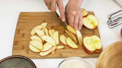 Woman slicing apples. Close up on a wooden cutting board on white background