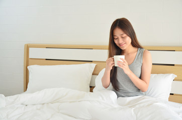 Asian woman in bed with hot coffee