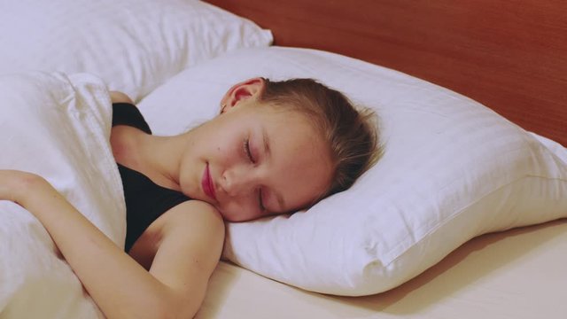 Cute young girl sleeping in bed. Lovely girl smiling while sleeping in bedroom. Sleeping, dreaming concept