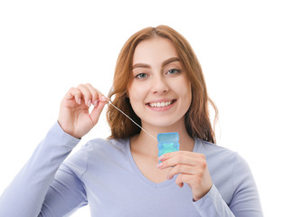 Beautiful young woman with dental floss on white background