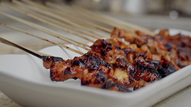 Placing grilled chicken satay on a plate