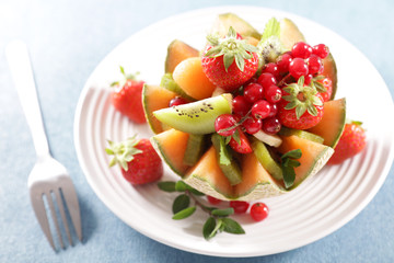 fruit salad in melon bowl with berry fruit, kiwi and banana