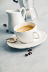 Coffee espresso in white cup with milk and coffee maker