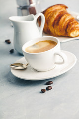 Coffee espresso in white cup with milk, jam and croissants.