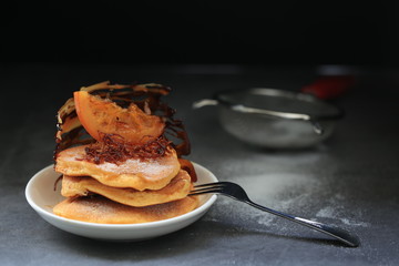 Homemade pancakes with orange candy top up and fork on dark background