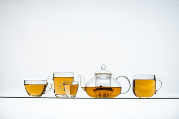 glass teapot and cups with hot tea on table, close view    