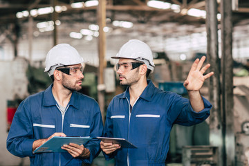 Engineer teamwork cooperate with worker to checking factory machine for safety and talking together.