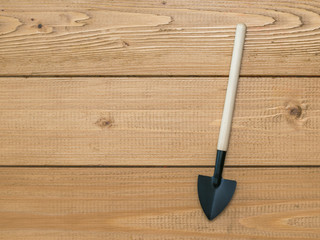 A shovel with a wooden handle on a background of wooden boards. A tool for cultivating the soil.
