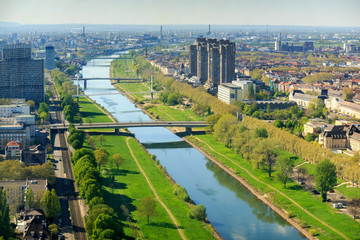 Top view of the embankment of the Neckar River. Bridges, green grass and trees. Tram lines. Different high-rise buildings. Mannheim. Germany.
