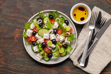Greek salad of fresh cucumber, tomato, sweet pepper, lettuce, red onion, feta cheese and olives with olive oil. Healthy food, top view