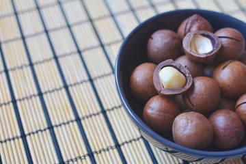 Macadamia nuts in a blue bowl close-up. Tasty and healthy snack.