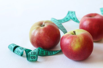 Ripe red apples with a centimeter on a white background, place for the inscription