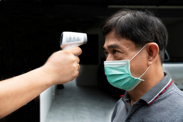 man wearing a mask, monitor the temperature with for safety, COVID-19