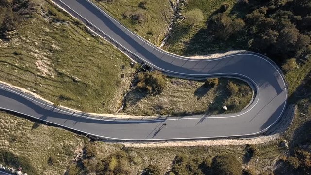 Aerial top View of a Skater Practicing Downhill down a Road in the Middle of the Forest in Andorra - Europe