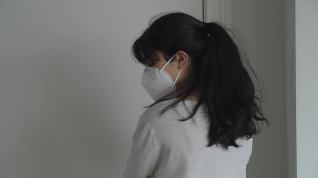 A young Latina woman enters door, and removes coronavirus mask, closeup 4k.