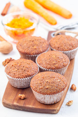 Homemade carrot cake muffins with walnuts on a wooden board, vertical