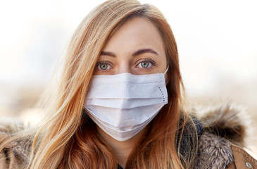 health, safety and pandemic concept - young woman wearing protective medical mask outdoors