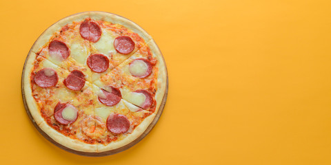 Flat lay pepperoni pizza isolated on bright yellow background. Pizza salami cut in slices. Fast food, junk food concept.
