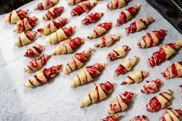 Grandmother making handmade tasty butter rolling cookies with fruit and berry jam on oven tray before baking at kitchen indoor. Rolled spin homemade healthy pastry preparing