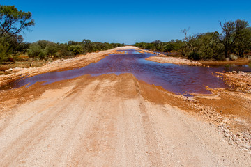 Flooded gravel road in the Australian Outback after the rain.