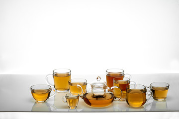 several tea glasses and a teapot on a glass table with a white background