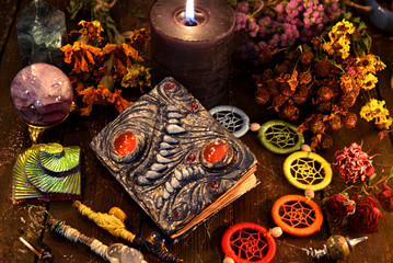 Witch grimoire with black candle, herbs and chakra decorations.