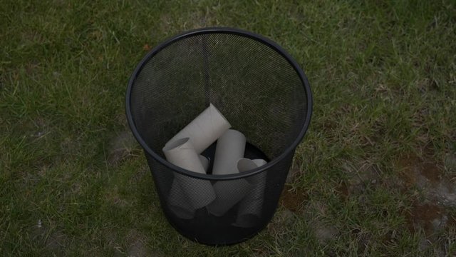 Downward view of empty toilet paper rolls randomly emptied into trash can, 180p to 30p slow-motion