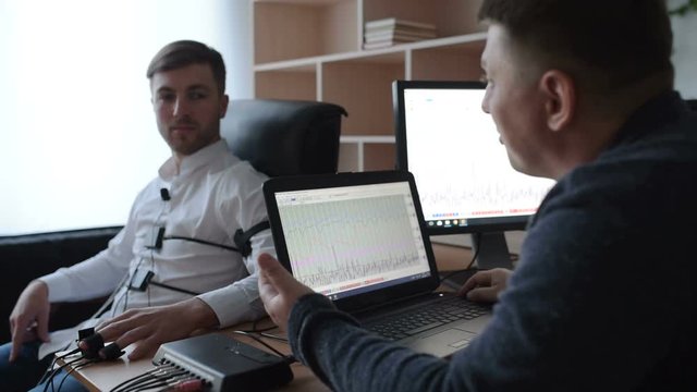 He admitted his guilt and wept. A suspicious man is passing a lie detector in the office. To ask questions. Polygraph test.