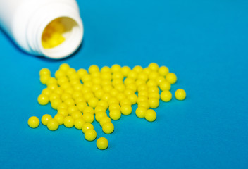 Round yellow vitamin C tablets on a blue background. Ascorbic acid close-up. Vitamin C for the treatment and prevention of colds. Virus protection.