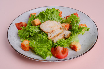 Healthy green organic caesar salad with cheese and croutons and grilled chicken served in white plate.
