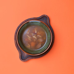 Fresh vegetable soup made of potatoes, mushrooms, carrot, red bell pepper and leek in bowl with parsley.