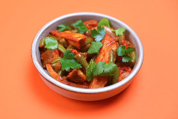 Stew of chicken meat with vegetables served in a bowl over bright orange background. Design banner with copy space.