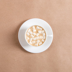 A white cup of coffee with marshmallows against the background of craft brown paper.