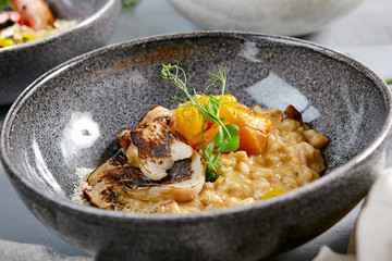 Risotto with white mushrooms and pumpkin in gray bowl