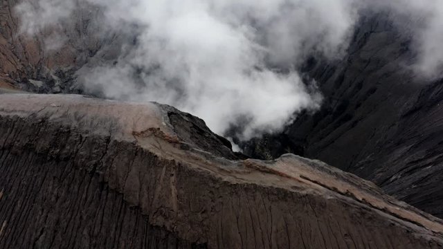 Aerial pullback from billowing active Mt Bromo Volcano