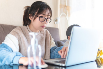 Woman working from home with children.  Young woman and cute child using laptop and tablet. Freelancer home workplace. Social distancing. Working from home. Stay home during pandemic. Hand sanitizer