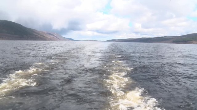 Loch Ness filmed handheld from the back a moving boat. One can see the trails of the boat in the water.