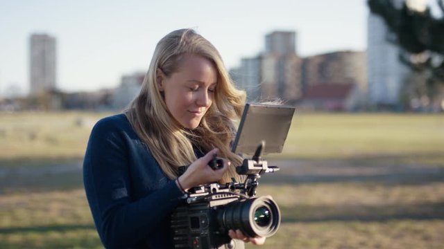 Female filmmaker and cinematographer shooting in beach park at sunset