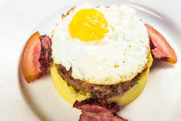 healthy homemade breakfast. fried egg and meat patty on top of smashed potato, decorated with bacon. food isolated on the white background