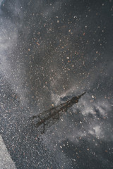 a television tower reflected in a puddle, a dark, dark photograph