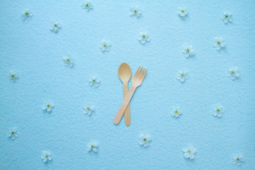 Eco-friendly disposable kitchenware and apple flowers on a blue background. The concept of zero...