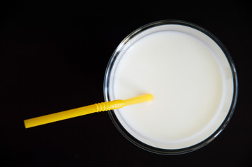 milk with a straw in a glass on a black table
